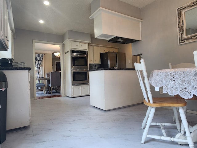 kitchen with white cabinets, a notable chandelier, double oven, and black fridge