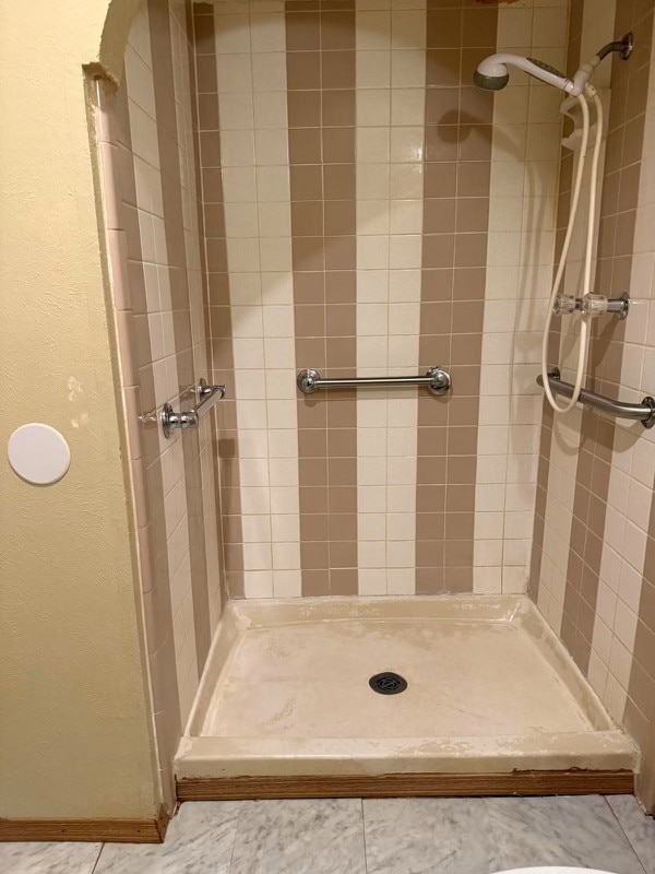 bathroom with tile patterned flooring and a tile shower