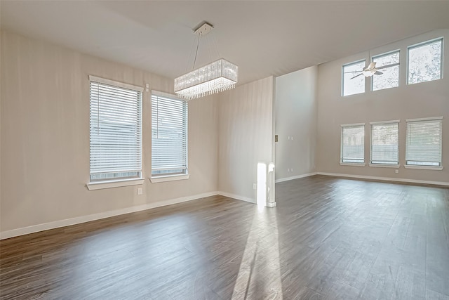 spare room featuring ceiling fan with notable chandelier and dark wood-type flooring