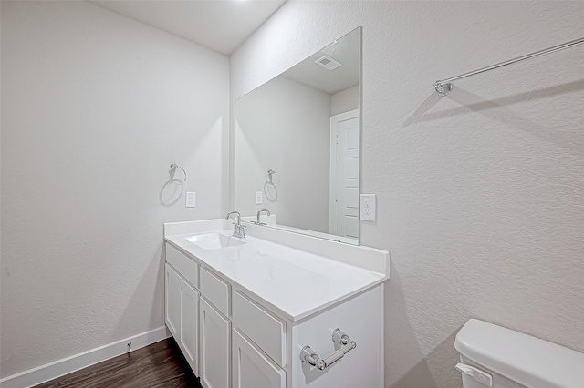 bathroom with toilet, vanity, and hardwood / wood-style flooring