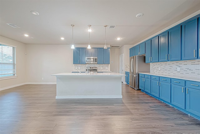 kitchen with a center island with sink, hanging light fixtures, and appliances with stainless steel finishes