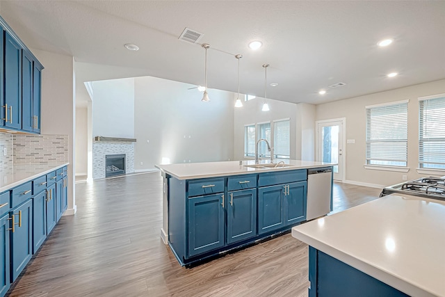 kitchen featuring a center island with sink, blue cabinets, sink, and appliances with stainless steel finishes