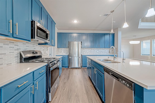 kitchen featuring hanging light fixtures, sink, blue cabinetry, and appliances with stainless steel finishes