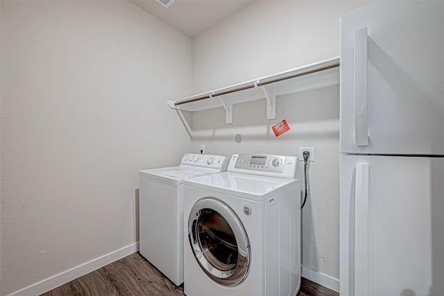 clothes washing area with separate washer and dryer and dark hardwood / wood-style floors