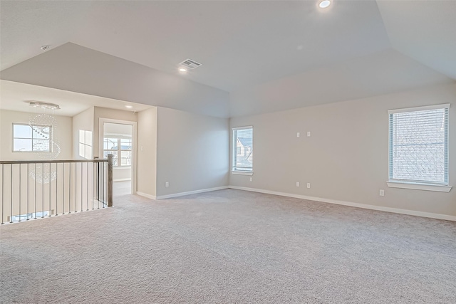 unfurnished room with a healthy amount of sunlight, light colored carpet, and lofted ceiling