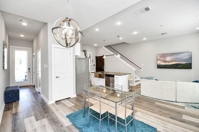 dining area featuring an inviting chandelier, light hardwood / wood-style flooring, and sink