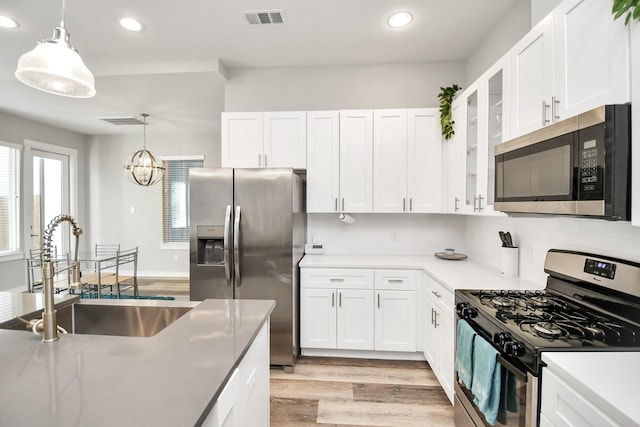 kitchen featuring stainless steel appliances, sink, decorative light fixtures, a notable chandelier, and white cabinets