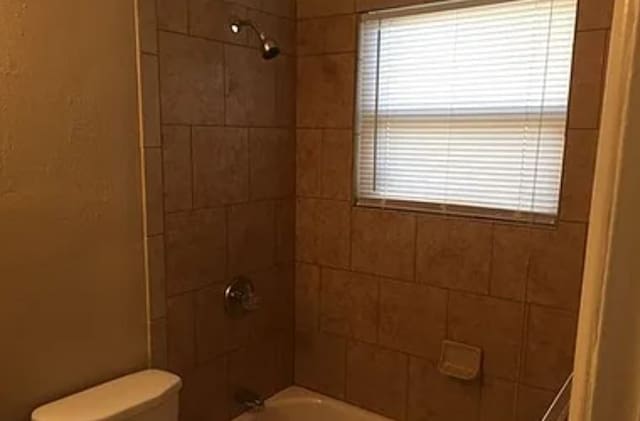 bathroom with toilet and tiled shower / bath