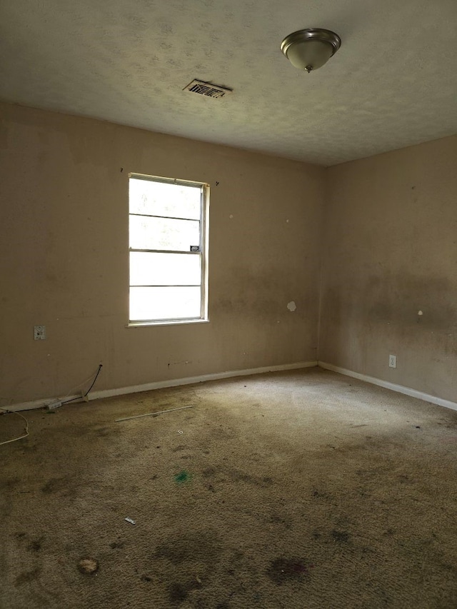 unfurnished room featuring carpet and a textured ceiling