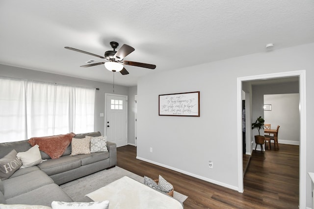 living room with ceiling fan, dark wood-type flooring, and a textured ceiling