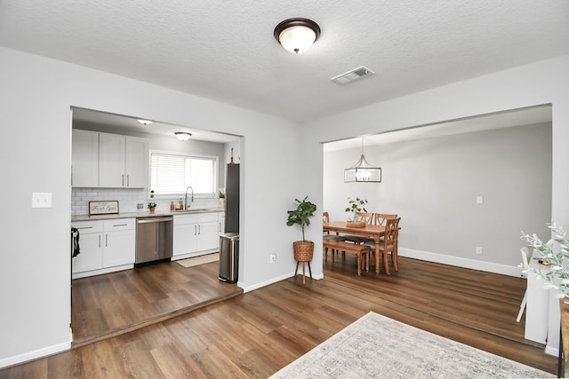 kitchen with white cabinetry, dark hardwood / wood-style flooring, pendant lighting, and stainless steel dishwasher