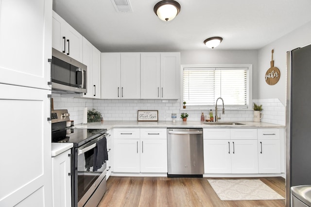 kitchen featuring white cabinets, light hardwood / wood-style floors, sink, and stainless steel appliances