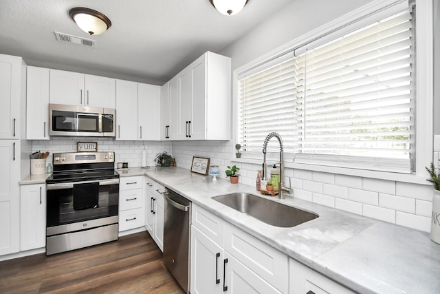 kitchen with decorative backsplash, stainless steel appliances, sink, white cabinets, and dark hardwood / wood-style floors