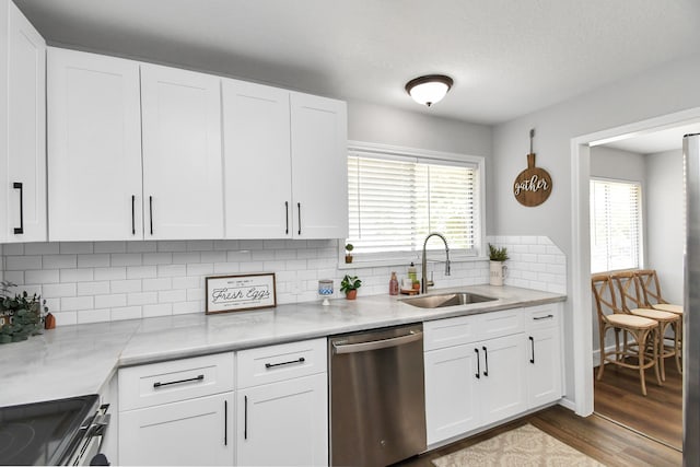 kitchen featuring appliances with stainless steel finishes, backsplash, dark wood-type flooring, sink, and white cabinetry