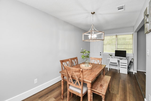 dining area with dark wood-type flooring and a notable chandelier