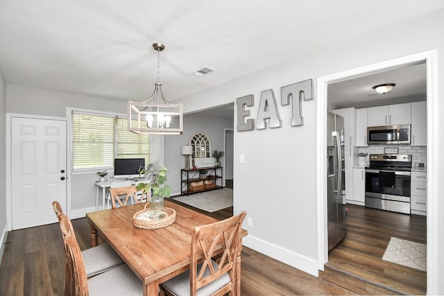 dining area featuring dark hardwood / wood-style floors, a textured ceiling, and a chandelier