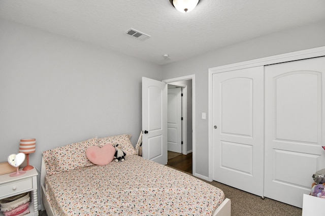 bedroom featuring a textured ceiling, dark carpet, and a closet