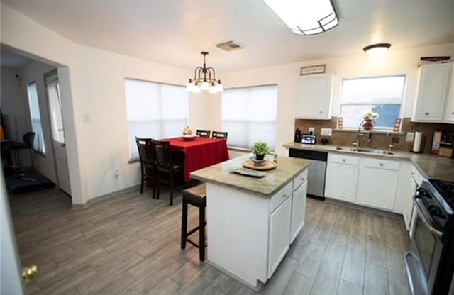 kitchen with hanging light fixtures, a center island, white cabinets, and stainless steel appliances