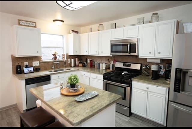 kitchen featuring white cabinets, a kitchen island, sink, and appliances with stainless steel finishes