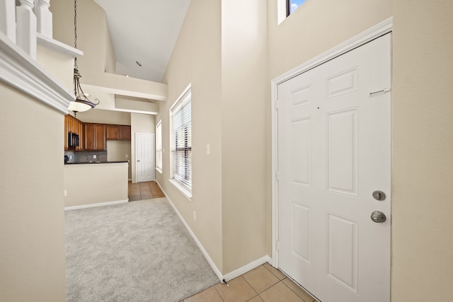 entrance foyer with a wealth of natural light, high vaulted ceiling, and light colored carpet