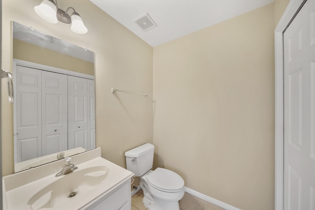 bathroom with toilet, vanity, and tile patterned floors