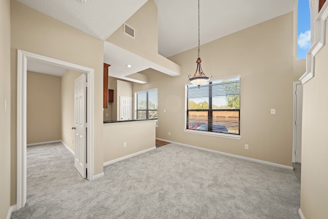 unfurnished room with a towering ceiling and light colored carpet