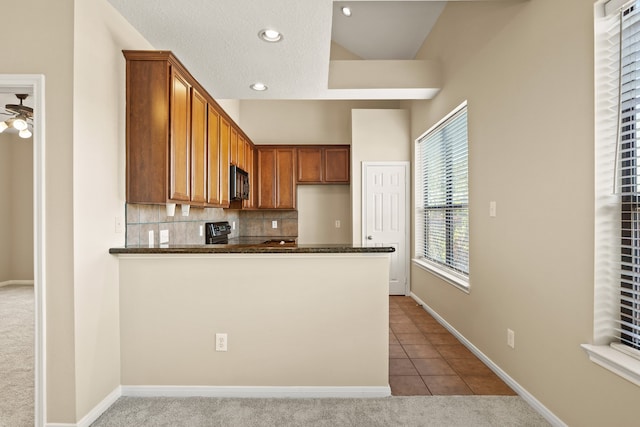 kitchen with decorative backsplash, dark stone counters, ceiling fan, black appliances, and light tile patterned flooring