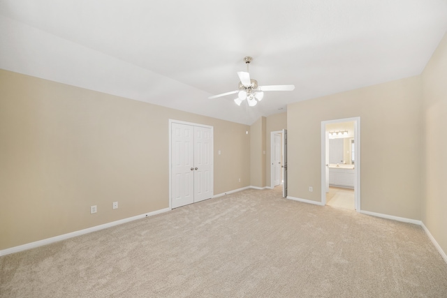 unfurnished bedroom with light carpet, a closet, ensuite bath, and ceiling fan