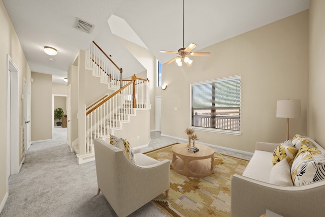 carpeted living room with a towering ceiling and ceiling fan