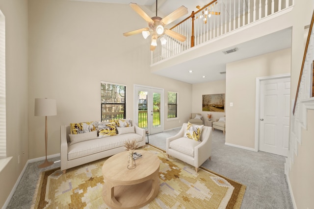 carpeted living room featuring ceiling fan, a towering ceiling, and french doors