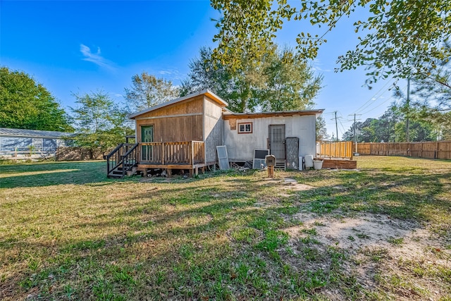 rear view of house featuring a lawn and a deck