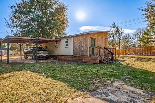 back of property with a lawn and a carport