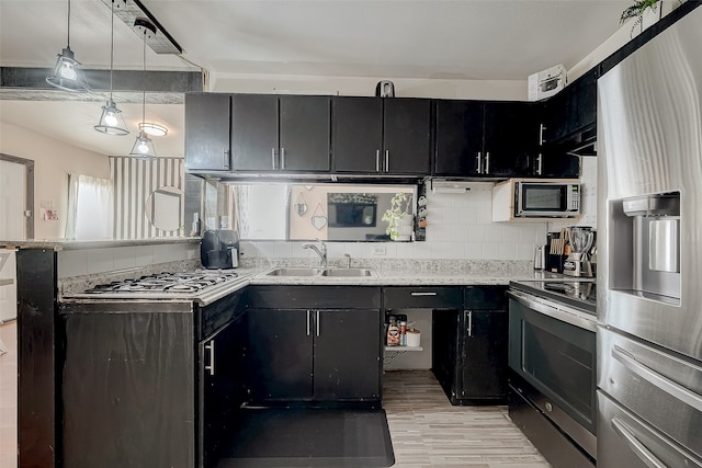 kitchen with pendant lighting, decorative backsplash, sink, and stainless steel appliances