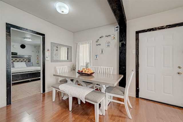 dining area featuring beamed ceiling and hardwood / wood-style flooring