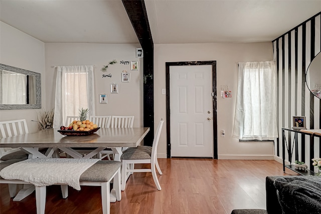 dining area featuring beam ceiling and light wood-type flooring