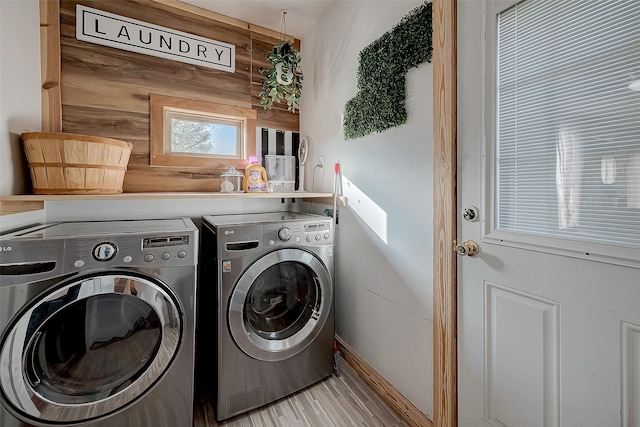 clothes washing area with wood walls and independent washer and dryer