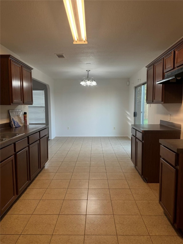 kitchen with dark brown cabinets, light tile patterned floors, and range hood