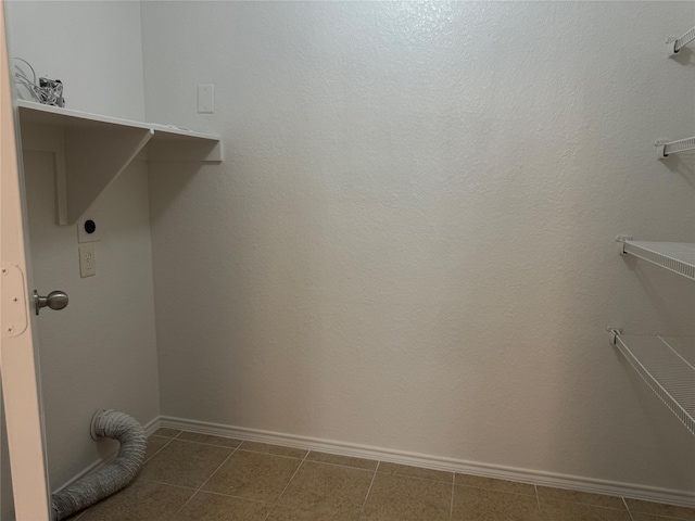 clothes washing area featuring electric dryer hookup and dark tile patterned floors