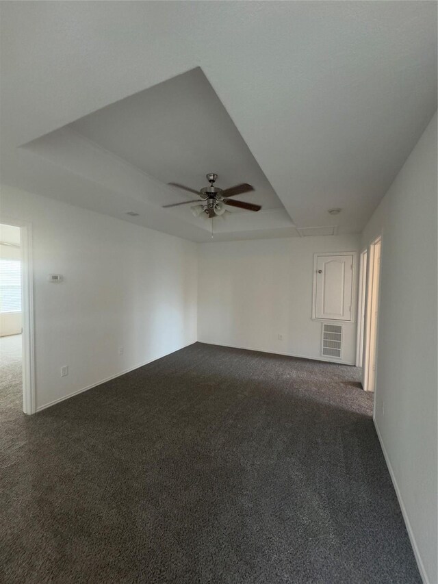 carpeted spare room with a tray ceiling and ceiling fan