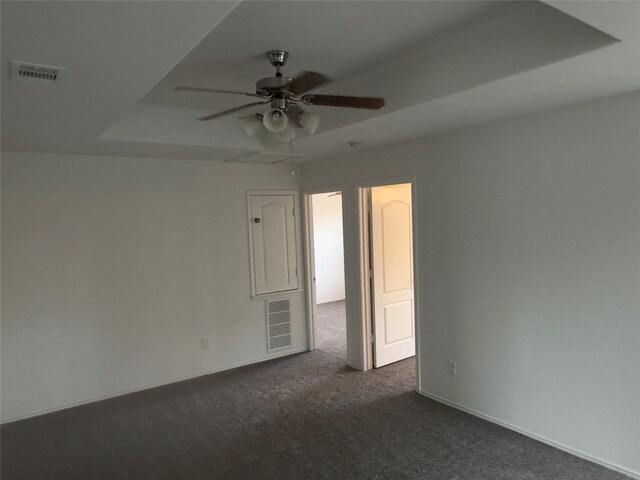 carpeted empty room featuring a tray ceiling and ceiling fan