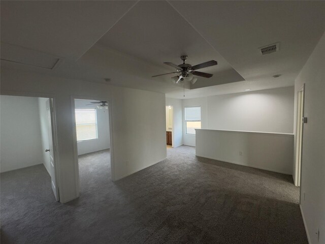 carpeted empty room featuring a tray ceiling, plenty of natural light, and ceiling fan