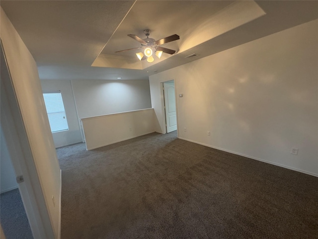 carpeted spare room with ceiling fan and a tray ceiling