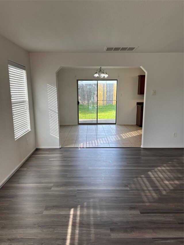 unfurnished room featuring dark hardwood / wood-style floors and an inviting chandelier