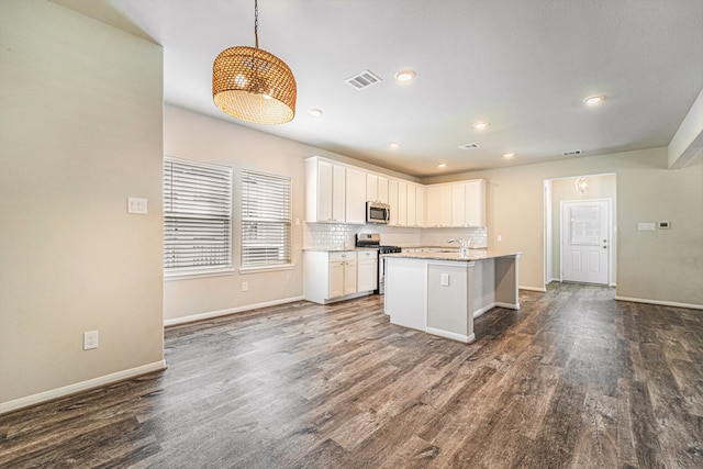 kitchen featuring dark hardwood / wood-style flooring, stainless steel appliances, white cabinets, hanging light fixtures, and an island with sink