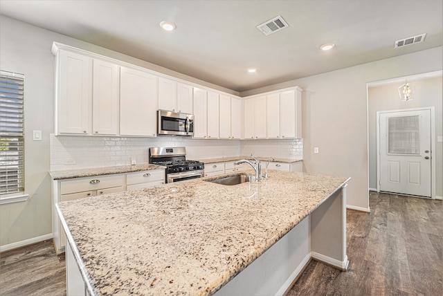 kitchen featuring white cabinetry, sink, light stone counters, appliances with stainless steel finishes, and hardwood / wood-style flooring