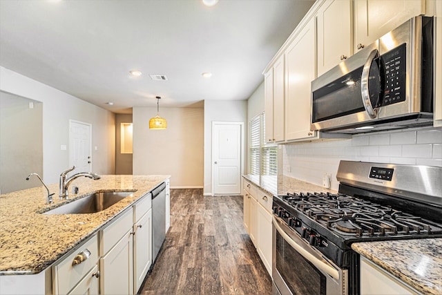 kitchen featuring sink, stainless steel appliances, light stone counters, dark hardwood / wood-style floors, and decorative light fixtures