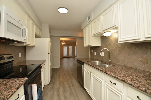 kitchen featuring white cabinetry, sink, stainless steel appliances, dark stone countertops, and light wood-type flooring