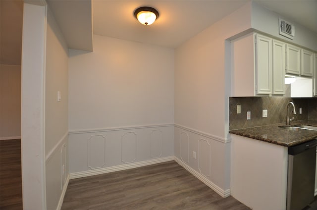 kitchen with dishwasher, dark wood-type flooring, sink, decorative backsplash, and dark stone countertops