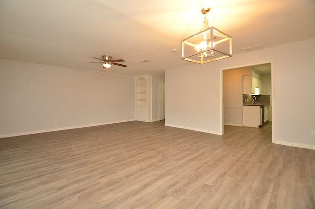 spare room with ceiling fan with notable chandelier and light wood-type flooring