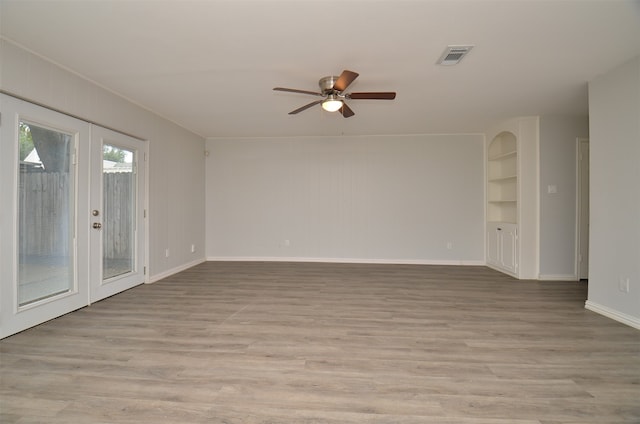 unfurnished room with french doors, light wood-type flooring, ceiling fan, and built in shelves